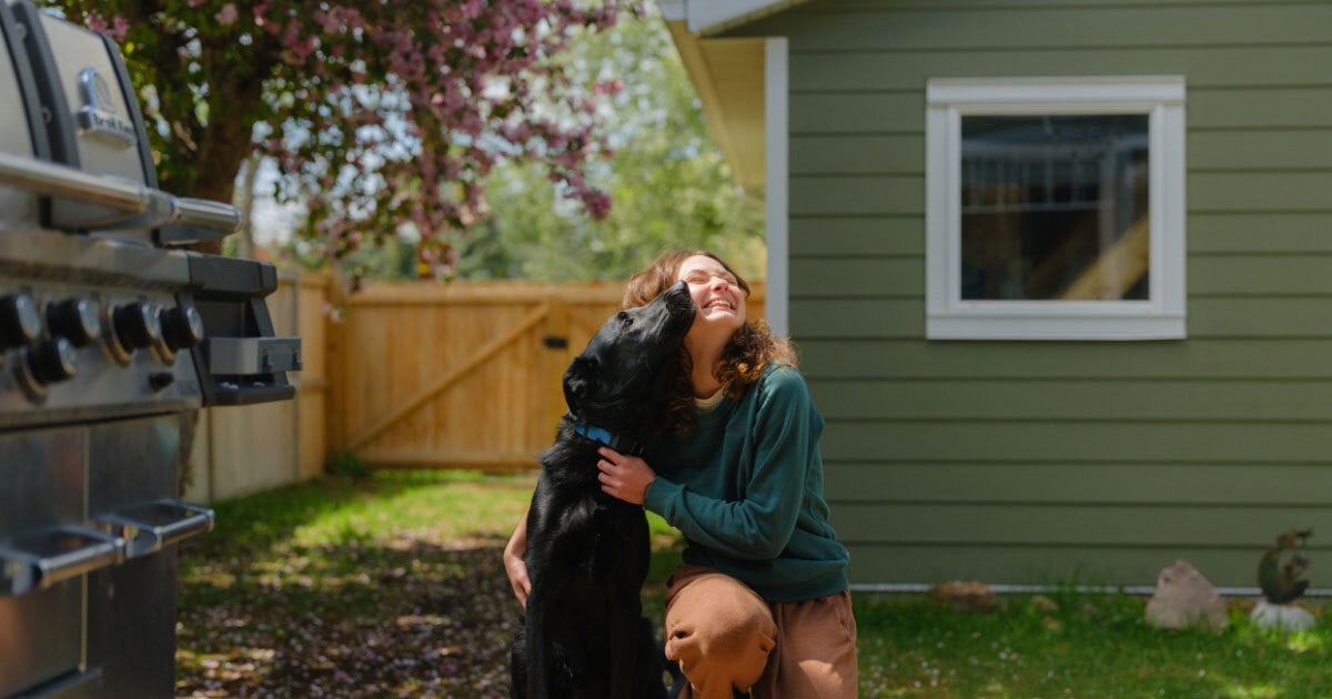 a first-time homebuyer in her yard with a dog
